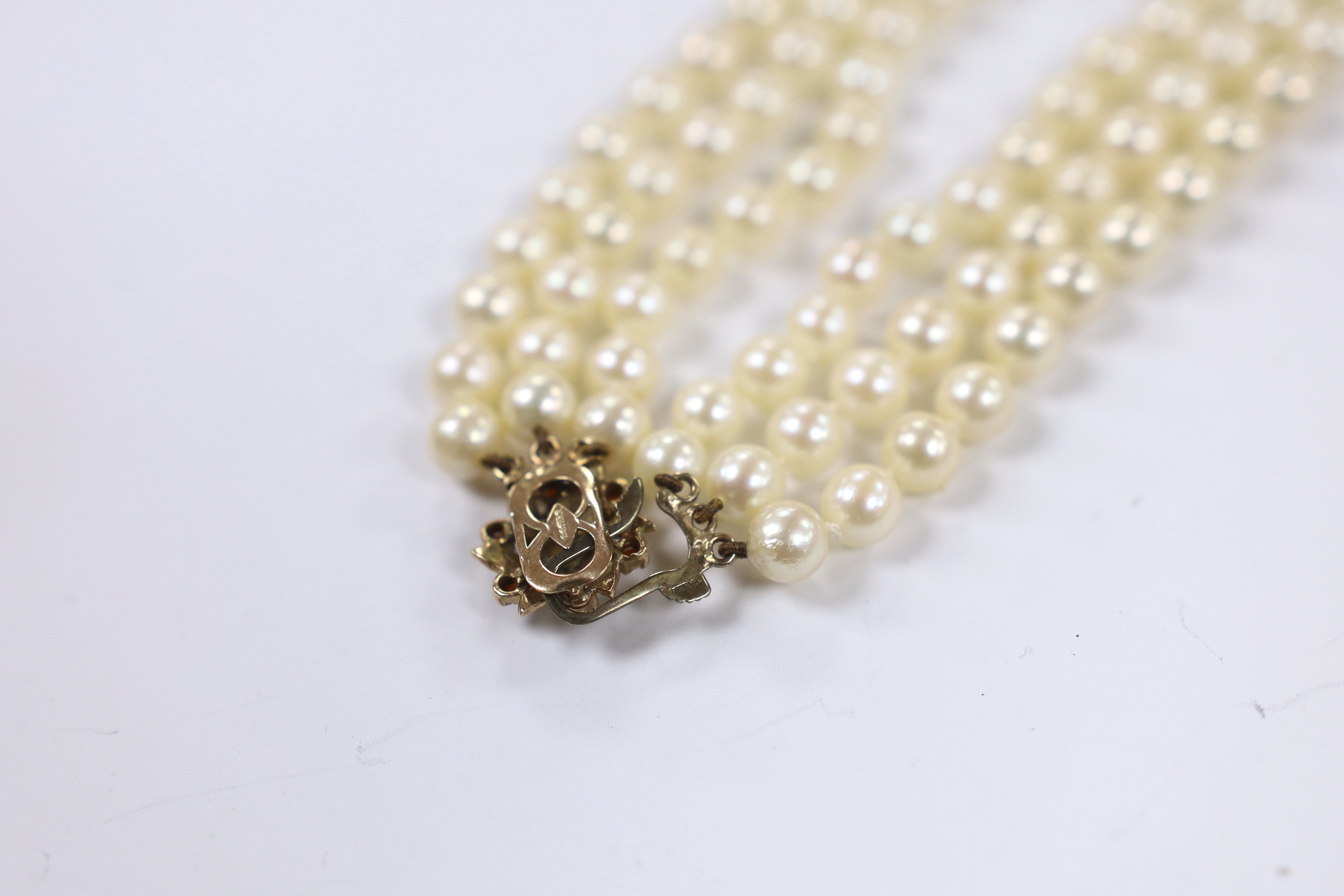 A triple strand cultured pearl choker necklace, with cultured pearl and garnet cluster set 9ct gold clasp, 36cm.